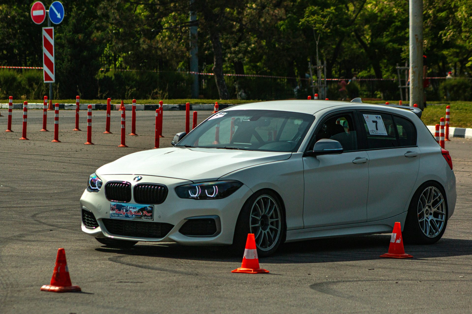 A white BMW is navigating an autocross course.