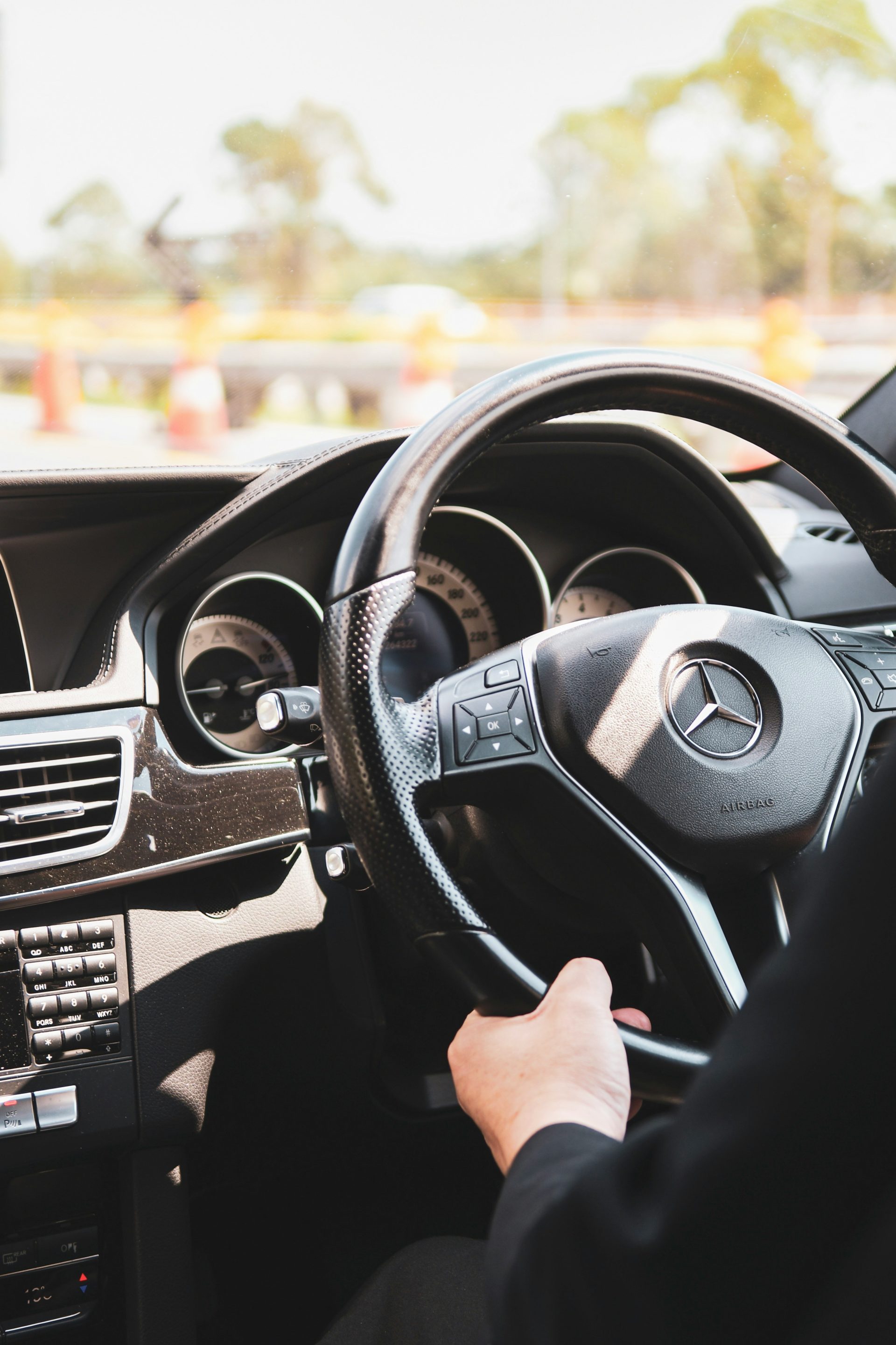 person in black shirt driving holding the mercedesbenz steering wheel