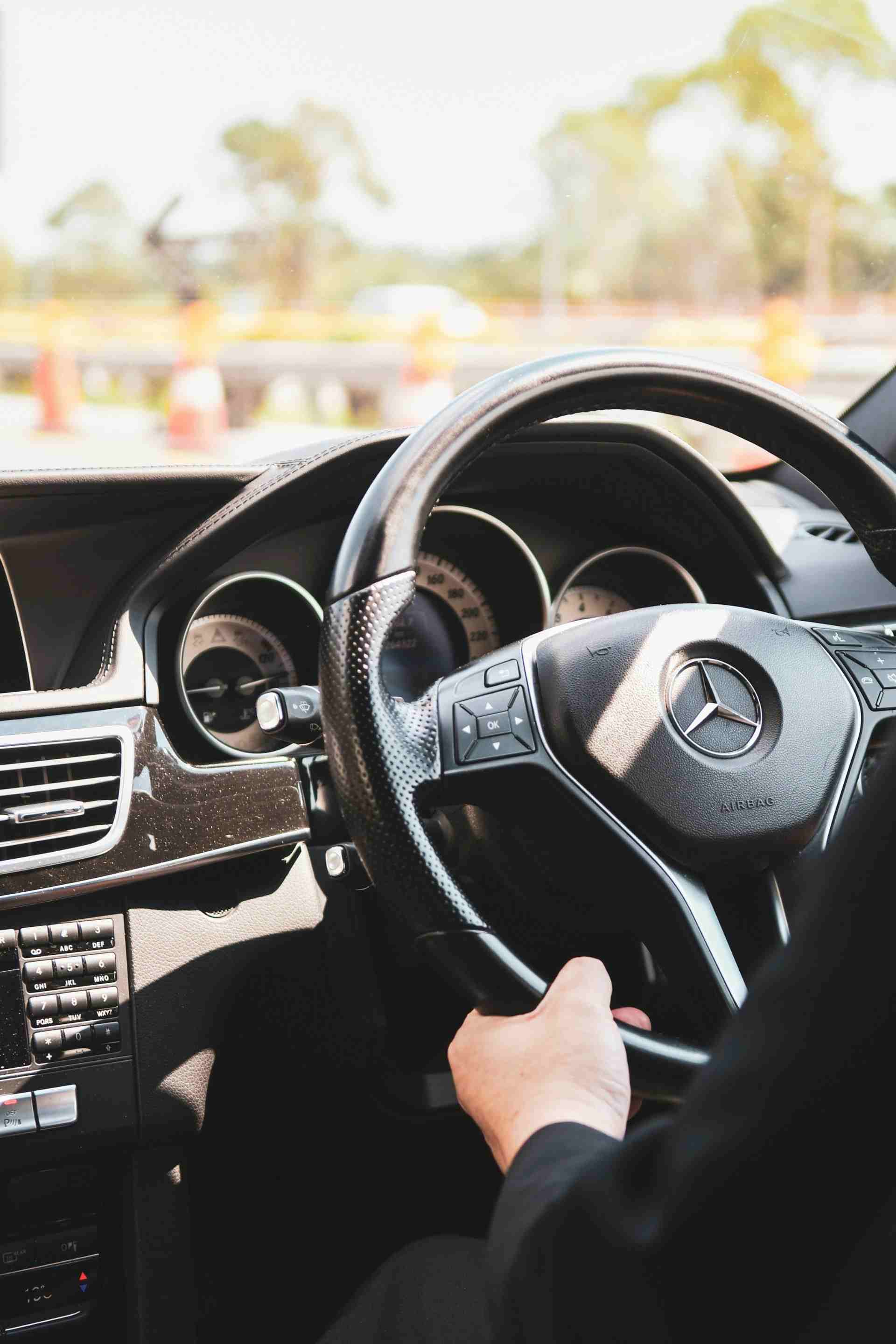 person in black shirt driving holding the mercedesbenz steering wheel